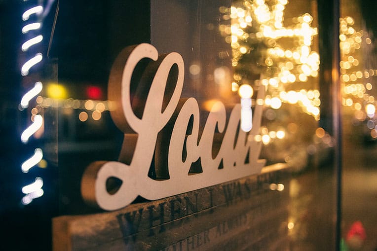 A carved wooden sign of the word Local in a shop window