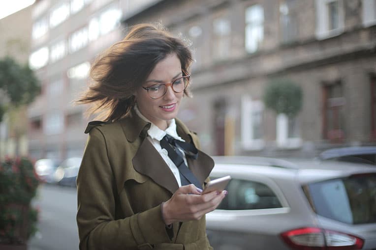 Woman in a suit using her phone walking down a city street